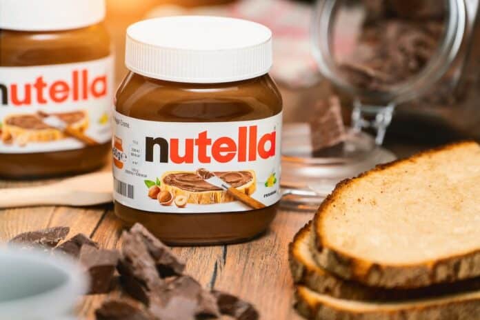 Pot of Nutella, the popular brand name of a sweetened hazelnut cocoa spread, introduced to the market in 1964 by Italian company Ferrero who celebrates 75 years anniversary in 2021 neonicotinoidi, nutella