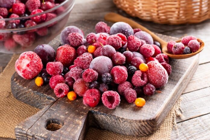 Mix of different frozen berries on a cutting board on table. Frozen Food. Food storage FRUTTI DI BOSCO EPATITE A