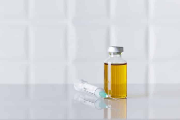 Bottle of injectable medicine and a syringe on white table. FERRO