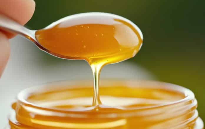A spoon with a honey jar on top of it being held by someone, AI MIELE ERETTILE
