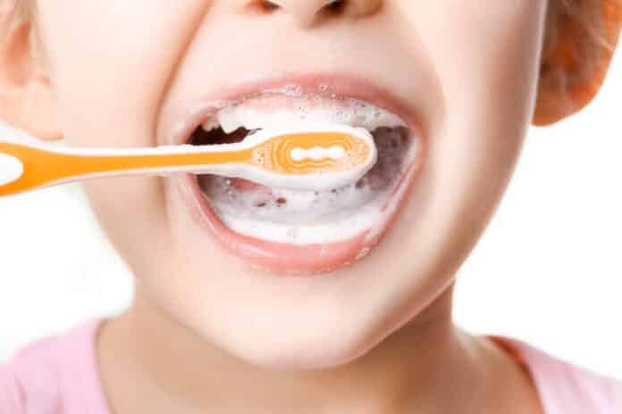 Adorable little girl brushing teeth on white background, closeup DENTIFRICI BAMBINI